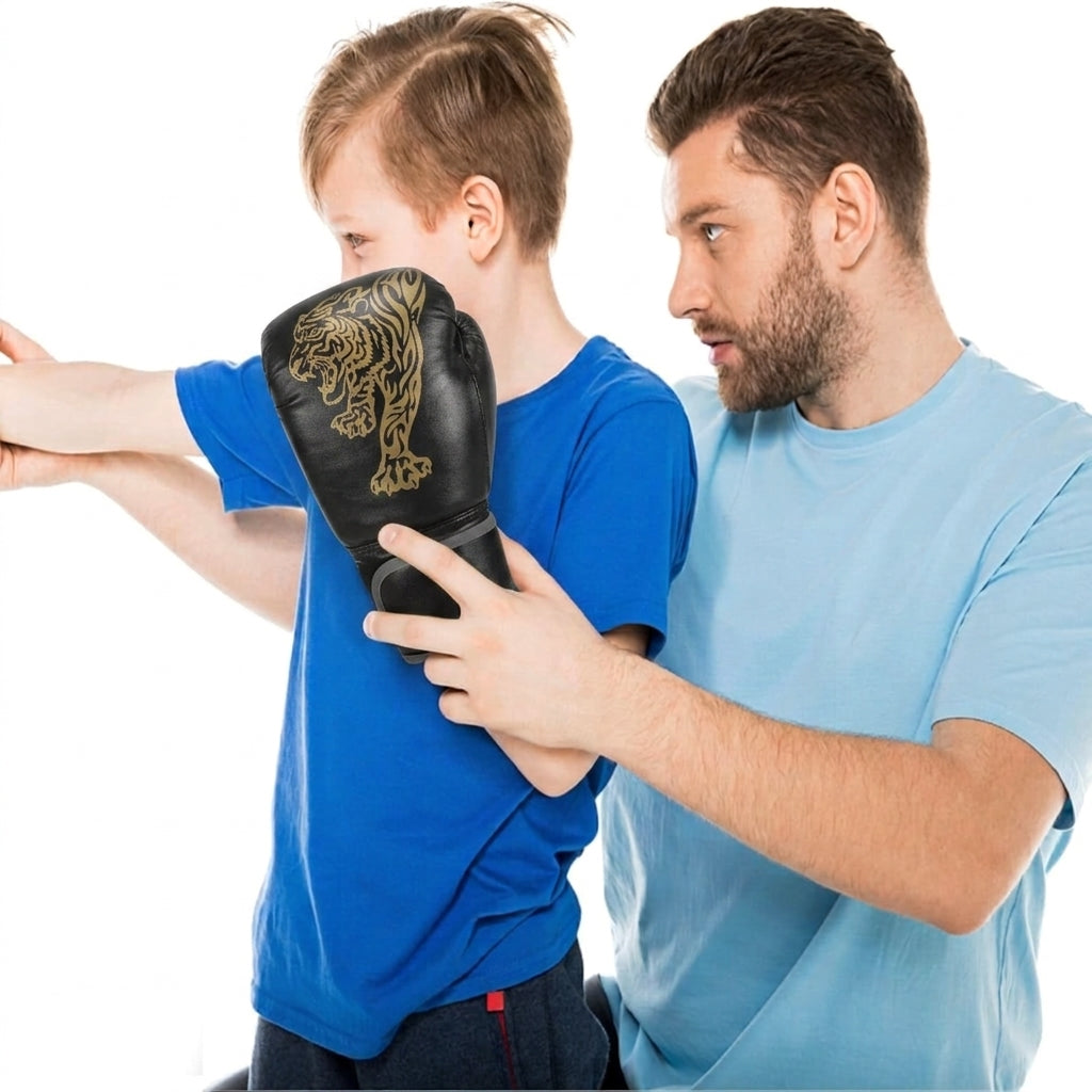 A man and a boy wearing a blue shirt demonstrate the use of a black boxing glove with a gold tiger design, set against a plain white background.