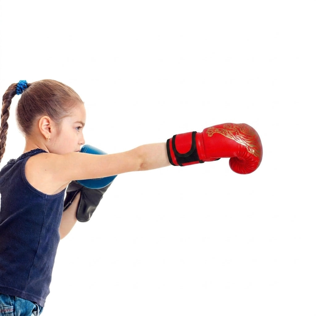 A young girl in a navy blue tank top and jeans is shown from the side, throwing a red boxing glove with a gold design while wearing a blue boxing glove behind it, against a solid white background.