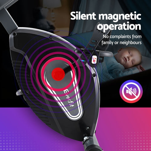 Folding Exercise Bike Everfit Magnetic X-Bike with silent magnetic operation next to a sleeping child.