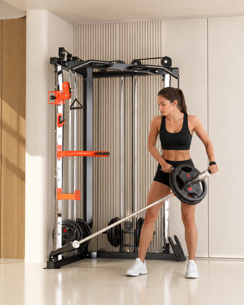 A woman in a black sports bra and shorts uses a cable pulley exercise machine with a barbell loaded with weight plates in a bright, modern gym setting.