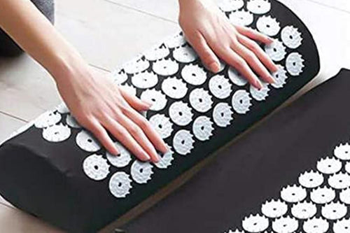 Person using an acupressure mat and pillow set to relieve tension with acupressure points.