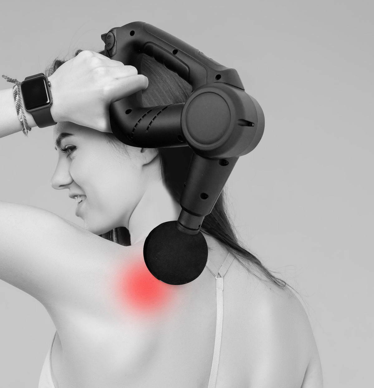 Massage gun providing vibration therapy on a woman's shoulder for muscle recovery and soreness relief.