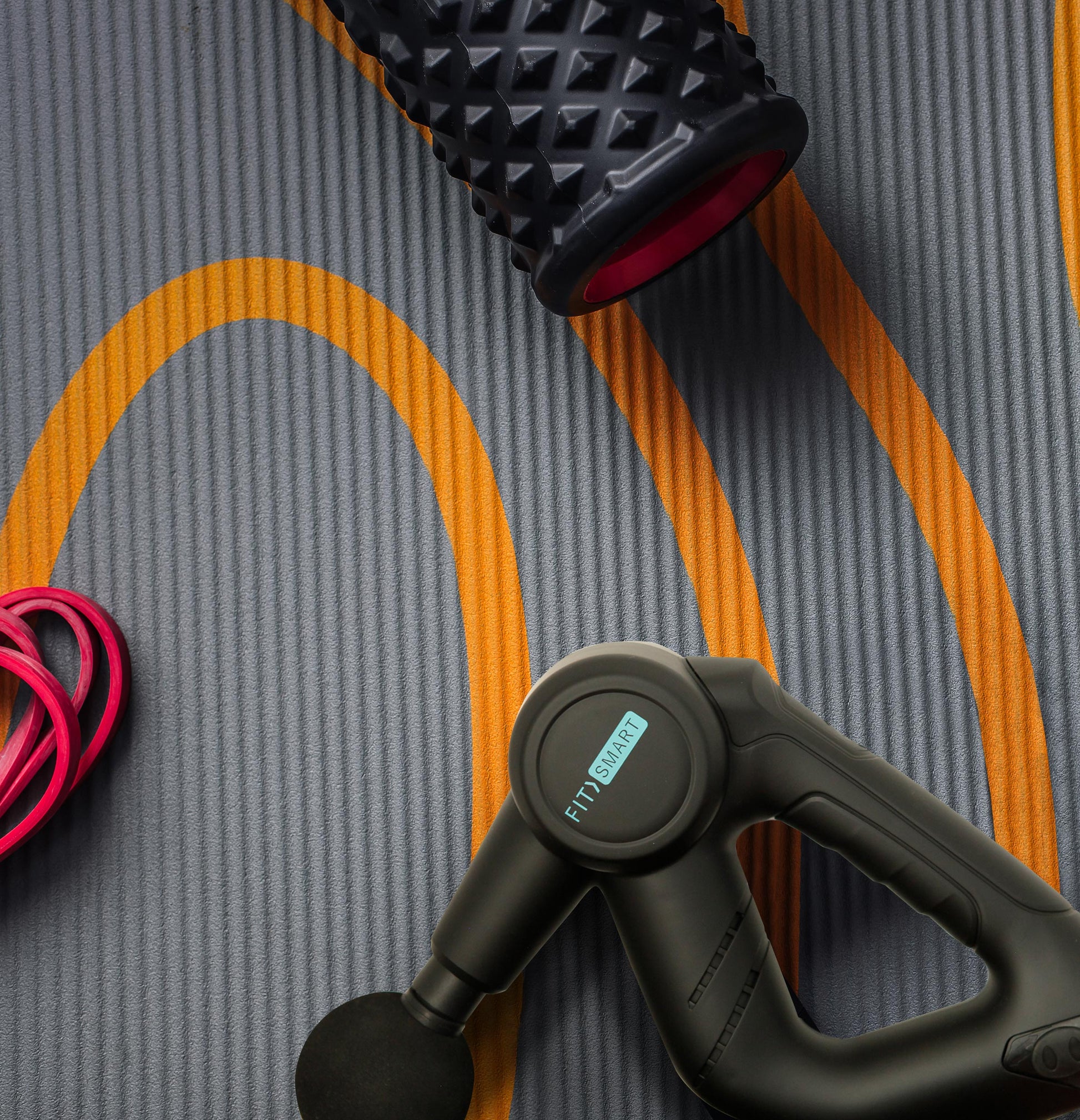 Massage gun and fitness accessories on a workout mat, ideal for muscle recovery and vibration therapy.