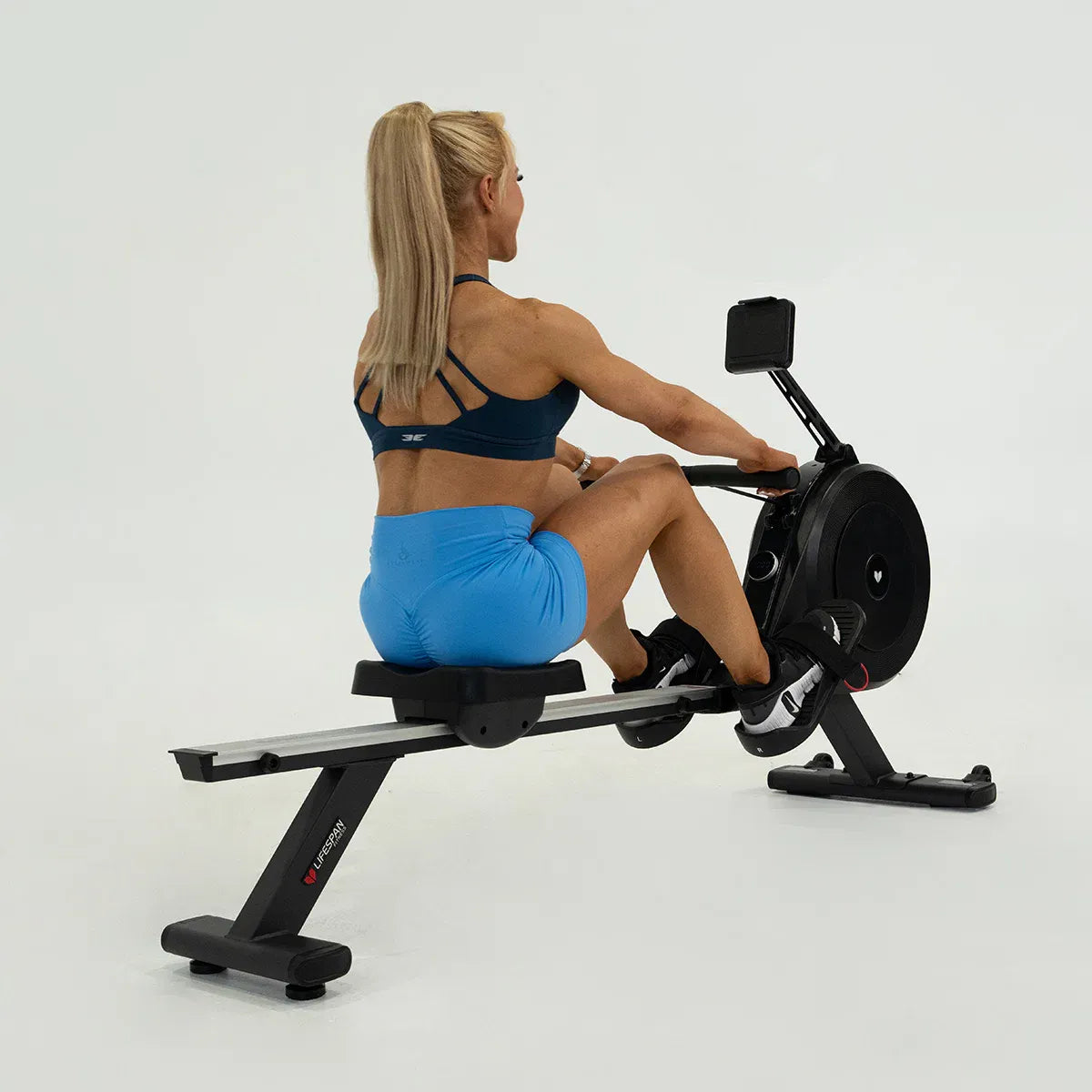 Woman exercising on a rowing machine with dual air/magnetic resistance, showcasing proper form.