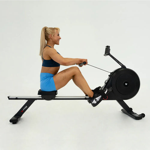 woman exercising on rowing machine with dual air/magnetic resistance, ROWER-500D, improving fitness and strength