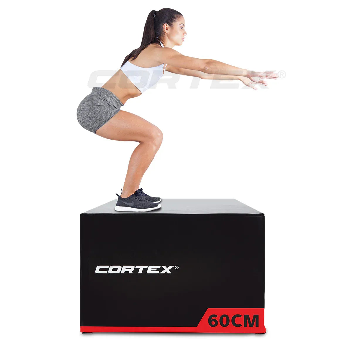 A woman performing a jump squat on a plyo box set by Cortex, height 60cm, ideal for fitness training.