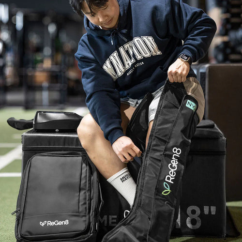 Person using ReGen8 Compression Recovery Boots for enhanced athletic recovery on a gym floor.