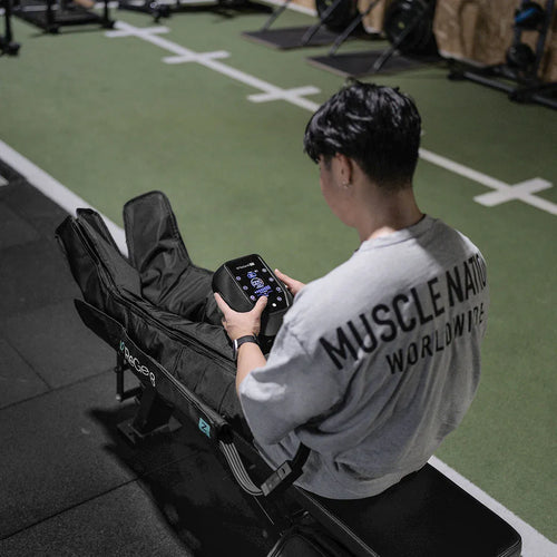 Person using ReGen8 Nyx Compression Recovery Boots in a gym setting for enhanced recovery.