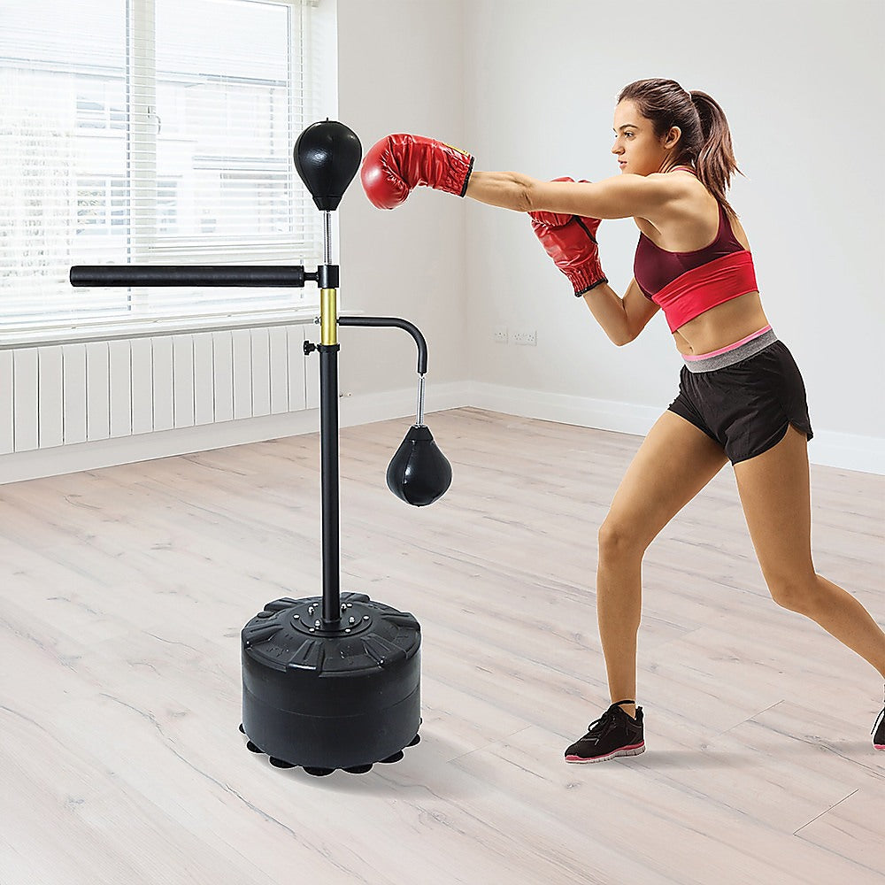 Woman using Free Standing Punching Bag with Reflex Speedball in home gym for boxing practice and fitness training.